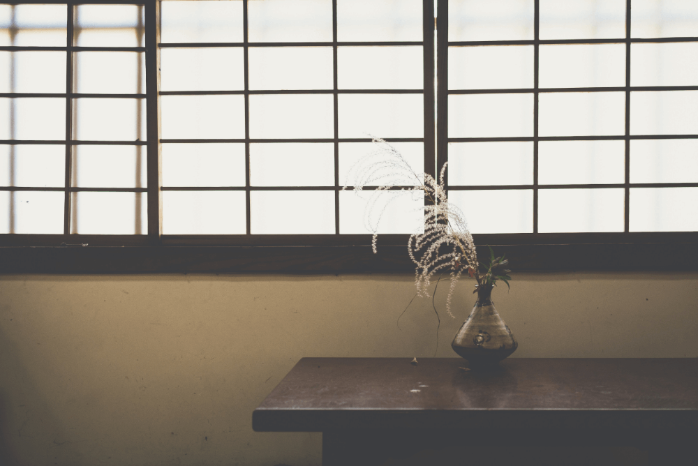 Vase on table by window with elegant shade.