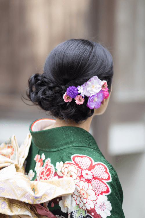 Japanese woman in traditional clothing with floral hair.